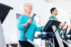 Older woman in blue working out on Elliptical Machine