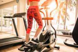 Femmina in pantaloni atletici rosa sulla macchina ellittica
