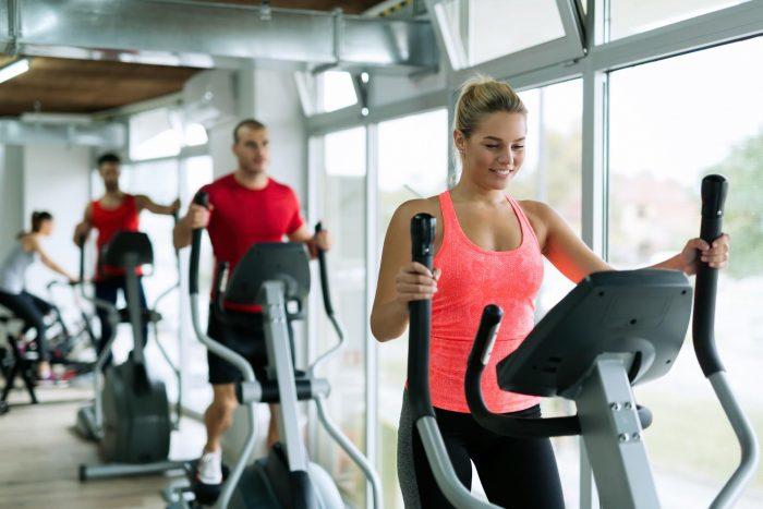 male and female exercising on elliptical machine