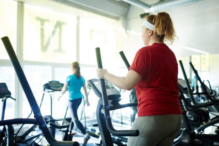 female on reed shirt on elliptical machine