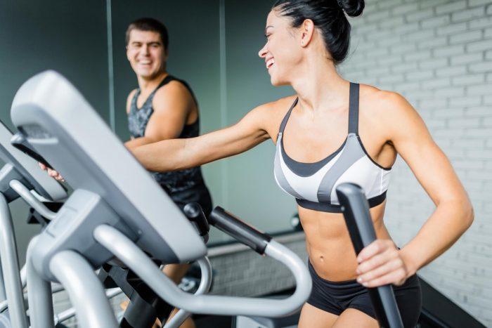 female on elliptical machine with a gym go-er beside her